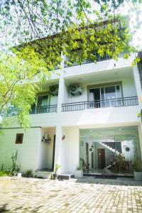 a white house with a balcony and a patio at Hotel Sapid Luck Yala Safari in Tissamaharama