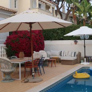 a patio with a table and umbrella next to a pool at Santos Villa in Quinta do Lago in Quinta do Lago