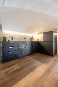 a kitchen with black cabinets and a wooden floor at Chalet l'ozio creativo in Castelnuovo Nigra