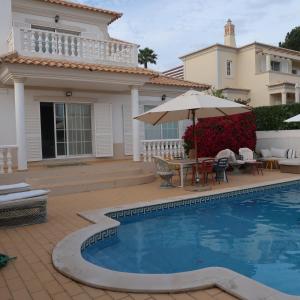 a house with a pool and a table and an umbrella at Santos Villa in Quinta do Lago in Quinta do Lago