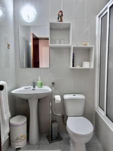 La salle de bains blanche est pourvue de toilettes et d'un lavabo. dans l'établissement Vale a Pena Residencial, à Trancoso
