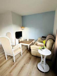 a living room with a couch and a table at Maison rénovée et chaleureuse proche du mémorial in Caen
