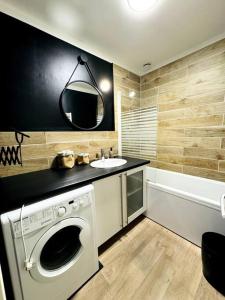 a bathroom with a washing machine and a sink at Maison rénovée et chaleureuse proche du mémorial in Caen