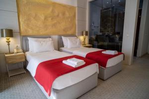 two beds in a hotel room with red and white sheets at Hotel Atina in Budva