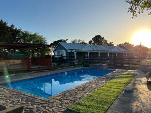 a swimming pool with a house in the background at Falaza Lodge Jozini in Bhokweni