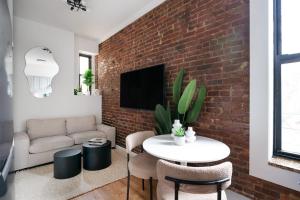 ニューヨークにある153-1G Newly Renovated 2BR Lower East Sideのレンガの壁のリビングルーム(白いテーブルと椅子付)