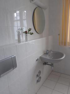 W białej łazience znajduje się umywalka i lustro. w obiekcie Fewo Muschel incl Kurkarte Parkplatz und strandnah w mieście Ahrenshoop