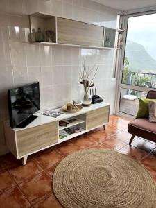 a living room with a flat screen tv and a rug at Kleines Haus am Meer in Arco da Calheta