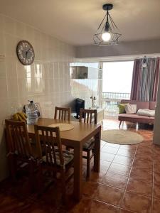 a kitchen with a table and chairs and a clock on the wall at Kleines Haus am Meer in Arco da Calheta