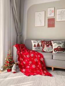 a living room with a red blanket and a christmas tree at LaLisa homestay Ecopark- Căn hộ thoải mái & ấm cúng Van giang Hung Yen in HÆ°ng YÃªn