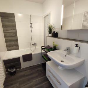 een witte badkamer met een wastafel en een bad bij Ferienwohnung Moritzwiese in Naumburg +12 foto's
