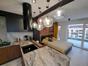 a bedroom with a bed and a kitchen with lights at Kima Apartament Bażantów 40 in Katowice