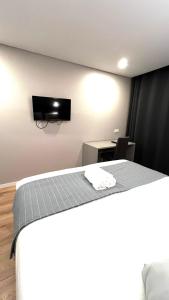 Habitación con cama y TV en la pared. en Apartamento Sociedade Farmaceutica, en Lisboa