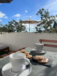 a table with two cups of coffee and cookies on it at Hotel San Miguel Menorca in Mahón