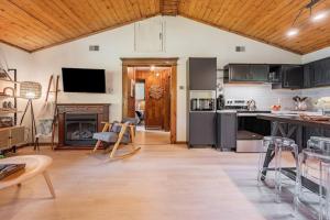 a kitchen and living room with black cabinets and a fireplace at Riverfront Cabin wFirepit Pool Table Porch WiFi in Hedgesville +31 photos