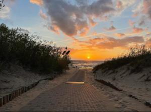 a brick path leading to the beach at sunset at Cozy Family River View Flat Near The Beach Seaside in Rīga