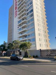 un'auto parcheggiata di fronte a un grande edificio di Departamento Vista al mar con estacionamiento a Concón