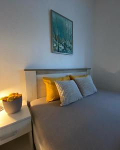 Vila Safir في لوزنيكا: سرير مع وسائد صفراء وصورة على الحائط