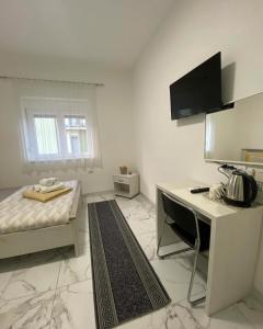a small white room with a bed and a desk at Vila Safir in Loznica