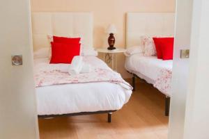 2 camas en una habitación con almohadas rojas y blancas en Piso junto a la Catedral, 4-5 personas, en Málaga