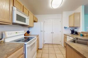 a kitchen with white appliances and wooden cabinets at Augusta Casita at SPI Golf Course in Laguna Vista