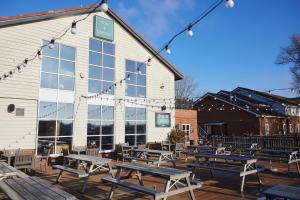 un grupo de mesas de picnic frente a un edificio en The Quays by Greene King Inns en Northampton