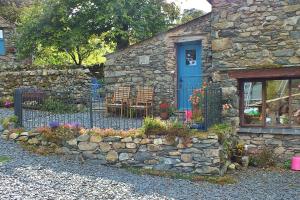una casa de piedra con una puerta azul y una valla en Finest Retreats - Woodend - The Buttery, en Ulpha