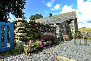an old stone house with a fence and flowers at Finest Retreats - Woodend - The Buttery in Ulpha