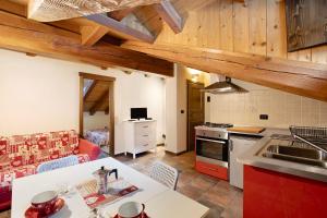 a kitchen and living room with wooden ceilings at Appartamento Aquila in La Salle