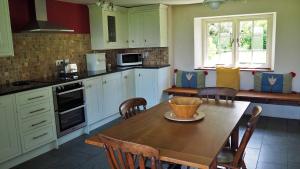 une cuisine avec une table en bois et des chaises ainsi qu'une salle à manger dans l'établissement Finest Retreats - Woodend - The Cottage, à Ulpha