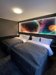 a room with two beds and a large painting on the wall at Sleephotels Cosmos in Hamburg