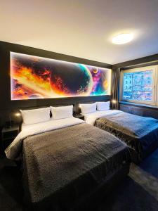 2 Betten in einem Zimmer mit einem großen Wandgemälde in der Unterkunft Sleephotels Cosmos in Hamburg