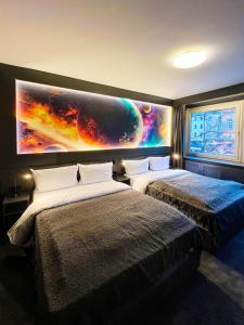 two beds in a room with a large painting on the wall at Sleephotels Cosmos in Hamburg