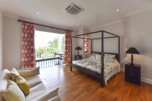 a bedroom with a canopy bed and a balcony at Chateau Elysium in Beau Vallon