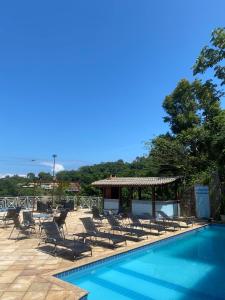 a swimming pool with lounge chairs and a gazebo at Pousada Ponta do Leste in Angra dos Reis