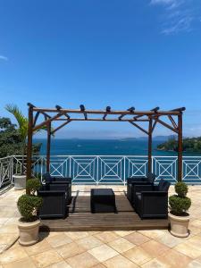 a deck with chairs and a pergola and the ocean at Pousada Ponta do Leste in Angra dos Reis