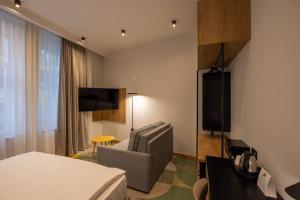 een hotelkamer met een bed, een stoel en een tv bij Hop Inn Rooms & Suites in Belgrado