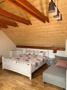 a bedroom with a white bed and a couch at Chalupa Štúrka in Polomka