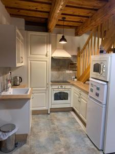 a kitchen with white appliances and wooden ceilings at Chalupa Štúrka in Polomka