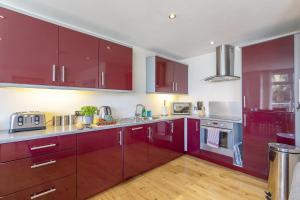 a kitchen with red cabinets and wooden floors at Anzac in Brixham