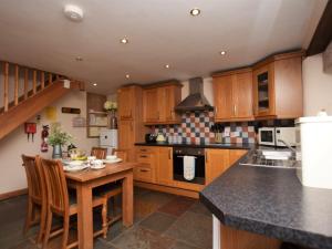 a kitchen with wooden cabinets and a table with chairs at 2 Bed in Bideford HIFOX in Shebbear