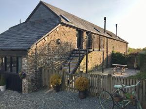 an old brick building with a wooden fence and a bench at 2 Bed in Bideford HIFOX in Shebbear