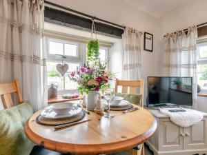 1 Bed in Crackington Haven HAWTH في Saint Gennys: غرفة طعام مع طاولة خشبية عليها زهور