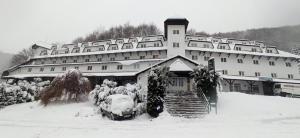 een groot gebouw met een auto in de sneeuw bij Bele Staze Apartman 86 in Brzeće