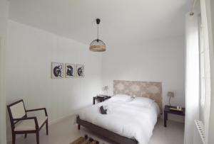 biała sypialnia z łóżkiem i krzesłem w obiekcie Gîte La Fontarelle pour 6 personnes - Clévacances 3 clés w mieście Saint-Caprais-de-Lerm