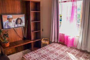 a bedroom with a bed and a tv on a wall at Aconchegante e lindo Apartamento da Graça perto do aeroporto e melhor churrascaria in Porto Seguro
