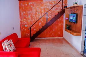 a living room with a red couch and a staircase at Aconchegante e lindo Apartamento da Graça perto do aeroporto e melhor churrascaria in Porto Seguro