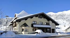 a building covered in snow with mountains in the background at Appartement Egart 3 in Resia