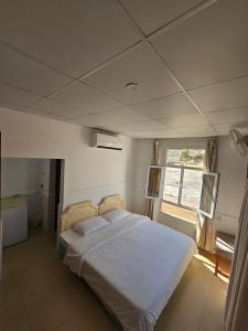 1 dormitorio con cama blanca y ventana en Wadi ashab chalets شاليهات وادي الشاب, en Sur