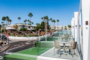 a balcony with a table and chairs and palm trees at Amor a Mar Starfish in Puerto del Carmen